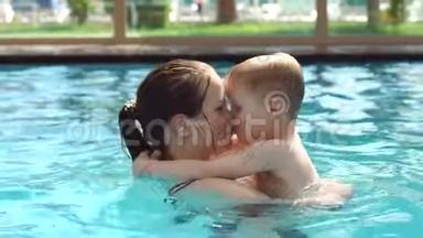 快乐的妈妈和她的小儿子在<strong>游泳池</strong>里游泳，她吻了<strong>婴儿</strong>。